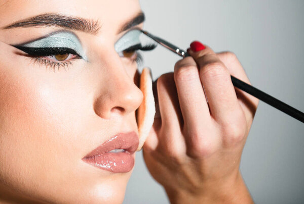 Makeup artist applies eye shadow. Hand of visagiste, painting cosmetics of young beauty model girl. Cosmetology, beauty and spa. Portrait of beauty model with make up on beauty face