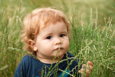 Parktaki bebek. Bebek yüzlü, yakın çekim. Küçük komik çocuk portresi. Sarışın çocuk, duygusal yüz.