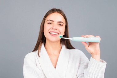 Elektrikli diş fırçası. Dişlerini diş fırçasıyla fırçalayan mutlu bir kadının güzel portresi.