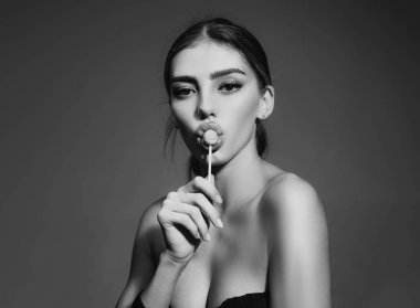 Ağzında lolipop olan çekici, çekici, çekici ve seksi bir kadının yakın plan portresi. Kırmızı şeker yalarken. Seksi kadın yüzü