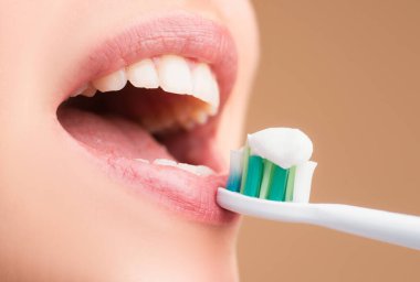 Yakın plan kadın dişlek gülüşü kopya alanı olan izole bir arkaplana karşı. Dişlerini fırçalayan bir kız. Güzel, genç bir kadın gülümsemesi. Diş sağlığı. Diş fırçasıyla yakın plan ağız. Diş fırçasıyla