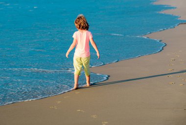 Çocuklar yaz tatilinde plajda. Yaz tatilinde sahildeki çocuk. Deniz, kum ve mavi gökyüzü. Mutlu çocuk deniz kenarında tatilde.