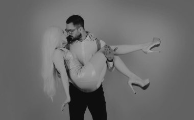 Aşık çift öpüşüyor. Komik Sevgililer Günü. Pembe izole edilmiş arka planda eğlenceli bir çift. Komik adam kollarında bir kadına sarılıyor.