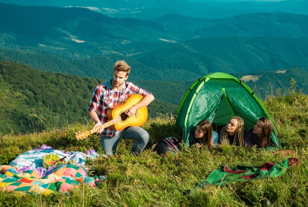 キャンプ一緒に楽しいですが 友情の観光キャンプでロマンチックなピクニック キャンプファイヤーの歌 若者のグループで一緒に キャンプにギターと女の子と幸せな男性の自由な時間を過ごす 旅行中の若者たち — ストック写真