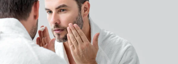 Cream treatment for male face. Beauty routine. Face of a beautiful man with perfect skin. Anti-aging and wrinkle. Concept of male beauty. Skincare and cosmetics concept. Skin care. Banner, copy space