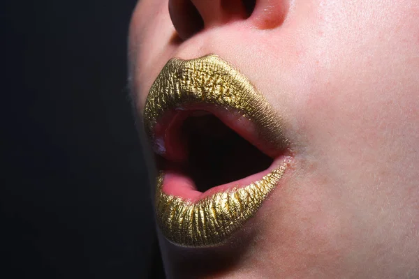 Gold lips, golden lipgloss on sexy lips, metallic mouth. Beauty woman mouth. Sexy girl golden lips, gold mouth. Glowing gold skin and gild lips. Surprised mouth