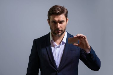 Gri izole arka planda kredi kartıyla takım elbiseli bir iş adamının portresi. Para yönetimi ve kredi puanı. Ödül parası. Kredi limiti. İnternetten alışveriş konsepti. Kredi geçmişi