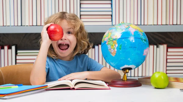 図書館で本とリンゴを持つ学校の少年 学校に戻る 本を持つ小学校の面白い小さな子供 子供の勉強と学習 — ストック写真