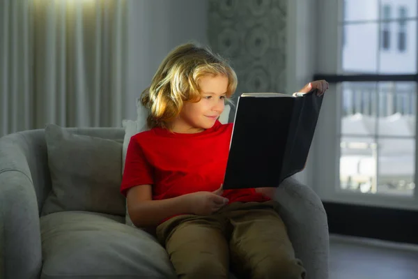 stock image Reading book child concept. Child reading book at home. Little boy sitting on couch in living room reading story book. Kid doing homework for elementary school