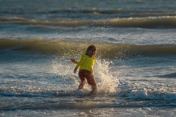 子供は熱帯の海のビーチリゾートで楽しみを持っています 面白い赤ちゃんの男の子は波の端に沿ってウォータープールでスプラッシュで実行されます アクティブな子供のライフスタイル 子供と一緒に夏休みに水泳活動をする人々 — ストック写真