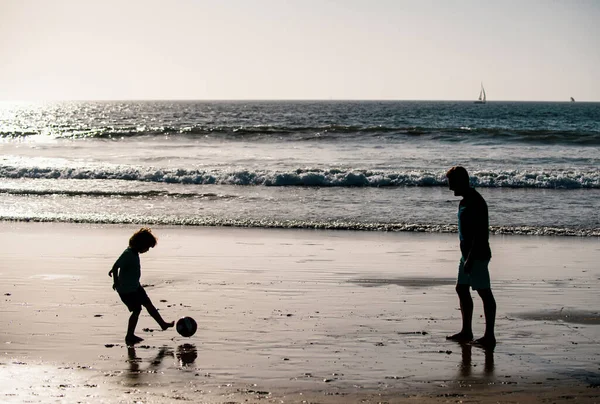 父と息子はビーチでサッカーやサッカーをします フレンドリーな家族と夏休みの概念 — ストック写真
