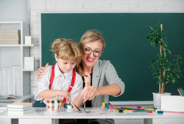 Öğretmenle birlikte öğrenen çocuklar. İlkokuldan çocuklar derste. Öğretmen ve küçük öğrenciler portresi, öğretmenler günü