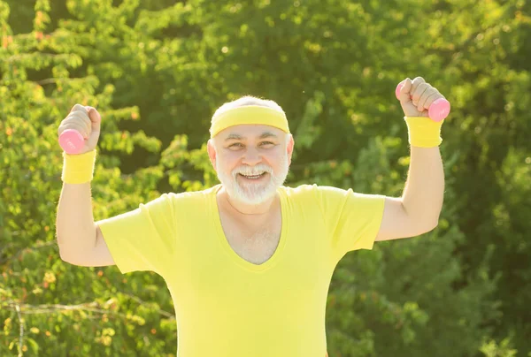 Kıdemli sporcu dambılları kaldırıyor. Yaşlı adam antrenmanı. Spor gibi.