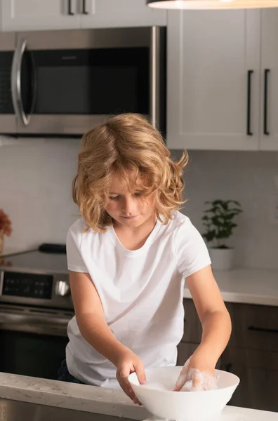 stock image Child cleaning dishes with sponge. Cleaning supplies. Help clean-up. Housekeeping duties. Kid wash dishes. A little cute boy washing dishes near sink in kitchen