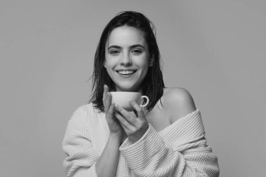 Kadın model elinde bir fincan kahve tutuyor. Kahve fincanı ile bornozlu mutlu kadın, stüdyo izole