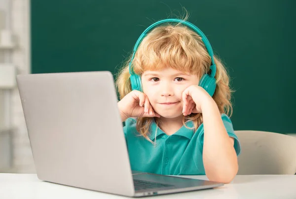 賢い学校の男の子 かわいい生徒はノートパソコンでヘッドフォンの書き込みを着て オーディオレッスンを聞くコンピュータを使用しています 小学校 — ストック写真