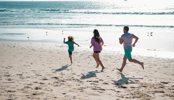 砂浜を走る家族 屋外でフレンドリーな家族のジョギングの概念 子供と熱帯夏休みに積極的な親や人々の屋外活動 — ストック写真