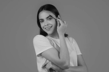 Güzellik salonunda fırçayla kaşlarını tarıyor. Uzun kirpikli ve kalın kaşlı bir kadın. Kaşlar, renkler ve kaplamalar için profesyonel bakım