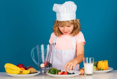 Aşçı önlüğü giymiş çocuk aşçı ve stüdyo arka planında izole edilmiş şef şapkası. Sağlıklı beslenme çocuklar için.