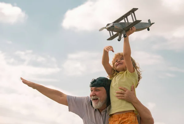 兴奋的小男孩和爷爷与飞机在户外的天空背景与复制空间 孩子梦想着飞翔 快乐的童年与爷爷在一起 — 图库照片