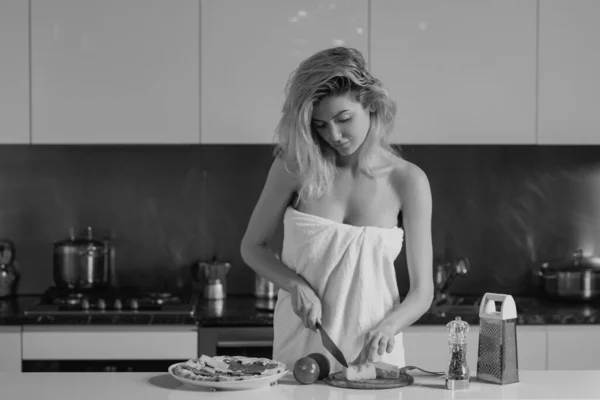 タオルの女性は台所でスリムな体を覆った 美しい女性は家で台所のテーブルの近くに立っている 朝の台所で主婦料理 — ストック写真