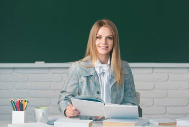 Üniversitede ya da okulda bayan üniversite öğrencisinin portresi. Yazı tahtası arkaplanında kopya alanı olan gülümseyen öğrenci kitabı