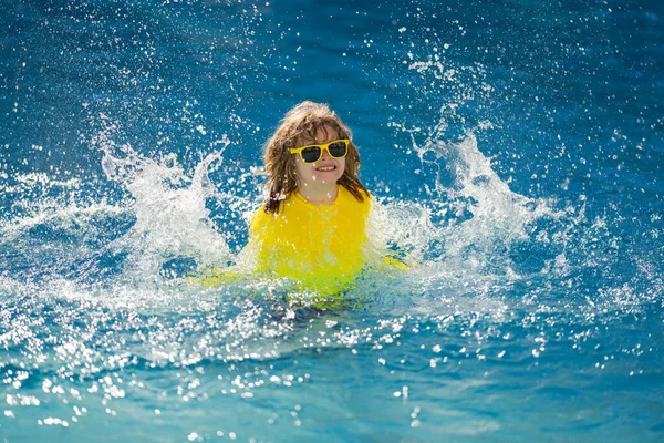 子供は夏の水プールで飛び散った プールで子供のスプラッシュ 興奮した幸せな男の子のプールでは 水の楽しさジャンプ 子供はスイミングプールに飛び込み 水をはねます プールサイドで子供が飛び散った — ストック写真