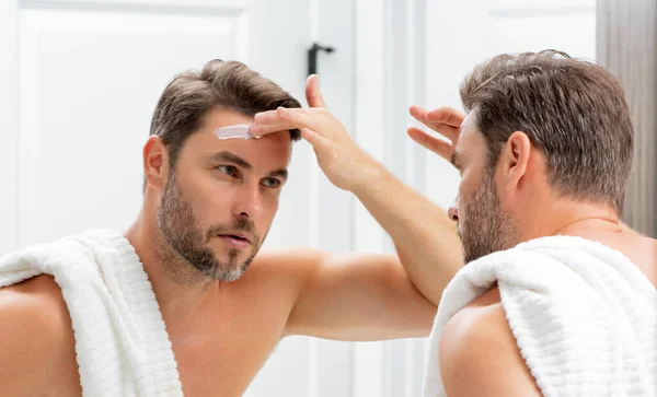 美容マンは 健康な肌 男性のスキンケアの概念のための保湿フェイスバームを使用します 男性の美しさとスキンケアの肖像画 シェービング後の健康的なきれいな顔 顔の治療 スキンケアの概念 — ストック写真