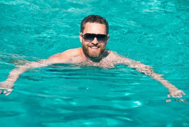 Yaz tatilindeki adam. Yüzme havuzunda dinlenen güneş gözlüklü adam. Yaz havuzu tatil köyü