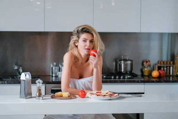 チーズ ソーセージ トマトの材料を持つ女性 若い女性が朝食を食べている 午前中に家でセクシーなスリムな女性 美しいです官能的な女性主婦でタオルで裸の肩 — ストック写真