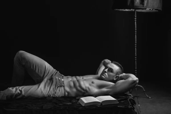 卧室里有个性感的家伙躺在床上看书的男人性和放松的概念 — 图库照片