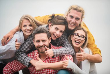 Farklı kültürlerden ve ırktan mutlu arkadaşlar başparmağıyla selfie çekiyorlar. Öğrenciler eğleniyor. Gençlik ve arkadaşlık kavramı. Bir grup arkadaş dışarıda kahkaha atıyorlar, iyi ve olumlu ruh hali.