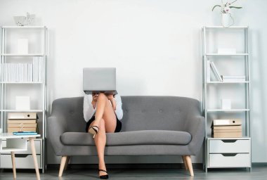 Seksi bacaklı baştan çıkarıcı sekreter ofiste kanepede oturur. Seksi iş kadını yüzünü dizüstü bilgisayarla kapatıyor. Şehvetli kız çalışanı. Güzel sekreter bacakları