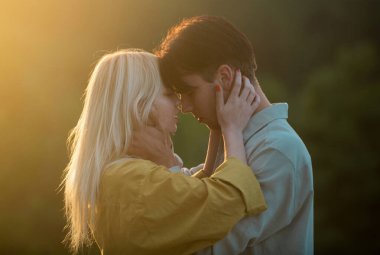 Şehvetli aşıklar gün batımında sarılıp öpüşüyorlar. Genç şehvetli kız arkadaşı, erkek arkadaşından tutkulu bir öpücük aldığı için mutlu. Yakışıklı genç adam kadınını kucaklıyor ve öpüyor.