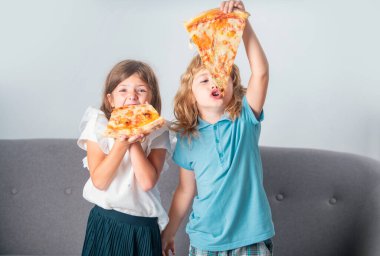 Pizza ve çocuklar, çocukların elinde pizza dilimleri. Çocuklar peynirli lezzetli fast food pizzası yiyorlar. Aç arkadaşlar için mutlu zamanlar. Komik çocuklar, küçük kız ve oğlan lezzetli pizza yiyorlar.