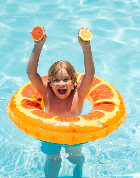 暑假的时候 小男孩在游泳池里漂浮着 游泳池里有橙子的孩子夏天的水果快乐的孩子在游泳池里玩游泳圈 — 图库照片