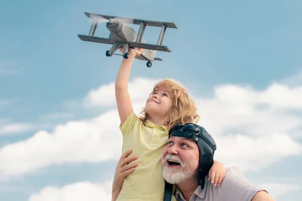 Grandfather and son enjoying play with plane together on blue sky. Family dream. Child dreams with plane. Grandfather and child son dream. Daydreamers. Dreams and imagination. Dreamy son