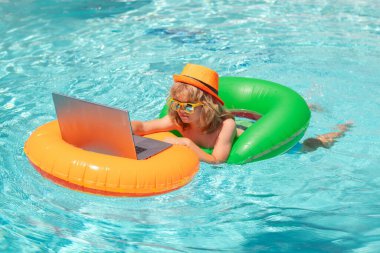 Küçük serbest çalışan, yaz seyahatinde olan bir iş adamı. Çocuk havuzda rahatlıyor, yaz suyunda dizüstü bilgisayar kullanıyor. Çocuk çevrimiçi çalışması ya da tropikal deniz sahillerinde çalışmak. Yaşam konsepti teknolojisi