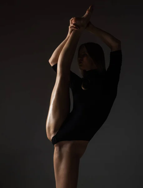 腿劈开 穿着黑色内裤的性感芭蕾舞演员伸展在黑色背景上 芭蕾舞的概念 性感的撑杆跳者身材匀称 身材匀称的漂亮性感女子 — 图库照片