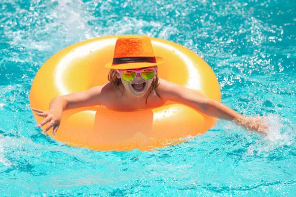 stock image Kid boy splashing in swimming pool having fun, leisure activity. Child boy swim with float ring in swimming pool. Kids summer holidays and vacation concept. Happy little boy with inflatable ring