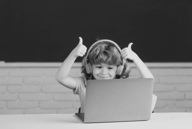 Okulda dizüstü bilgisayar ve kulaklık kullanan okul öğrencileri.