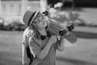 Yaz çocukları modası. Kaykaylı çocuk. Çocuk kaykay tahtası. Yazın okul çocukları için sağlıklı bir spor ve aktivite. Spor eğlencesi