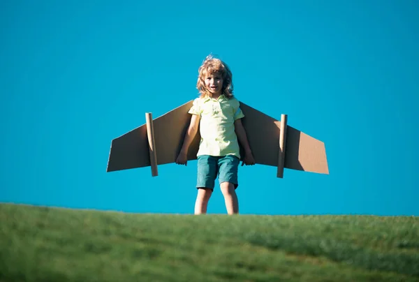Child to be pilot. Kid with paper wings flying. Summer vacation and travel concept. Funny child boy with toy cardboard airplane wings fly on sky. Kids dreams of traveling in summer in nature