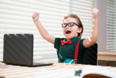 Çocuk ödevini evde dizüstü bilgisayarla yapıyor. Çevrimiçi eğitim konsepti, ev okulu öğrencisi