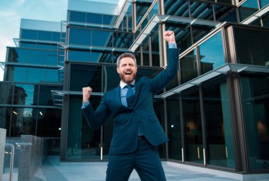 Yönetici işadamı. Modern ofis yakınlarında takım elbiseli bir CEO portresi. Şirket binasının önünde duran mutlu lider.