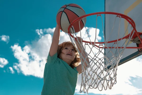 小孩篮球选手在蓝天背景下灌篮 那孩子在做运动 — 图库照片