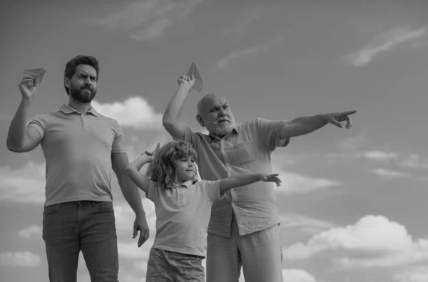 Three generations of men together, portrait of smiling son, father and grandfather with a toy airplane. Child boy playing with plane and dreaming future. Journey travel trip concept