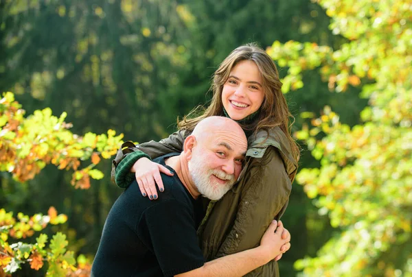 stock image Happy elderly father and daughter enjoying tender autumn moment, smiling. Grown up daughter hugging mature man from back, two generations having fun together