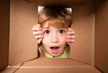 Çocuklar için karton kutuları açıyorum. Neşeli şirin çocuk hediyesini açıyor. Kutunun içinden görüntüle. Yakın çekim çocuk yüzü.