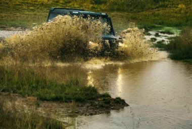 Off-road yarışında su sıçraması. Kirli arazi aracı yarışı. Çamurlu bir yolu olan kırsal bir arazide tekerlek yakın.